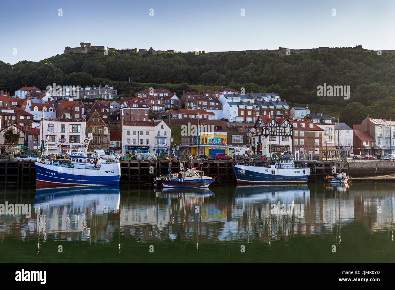 Fischerboote vertäuten im Hafen von Scarborough, mit Scarborough Castle im Hintergrund. Stockfoto