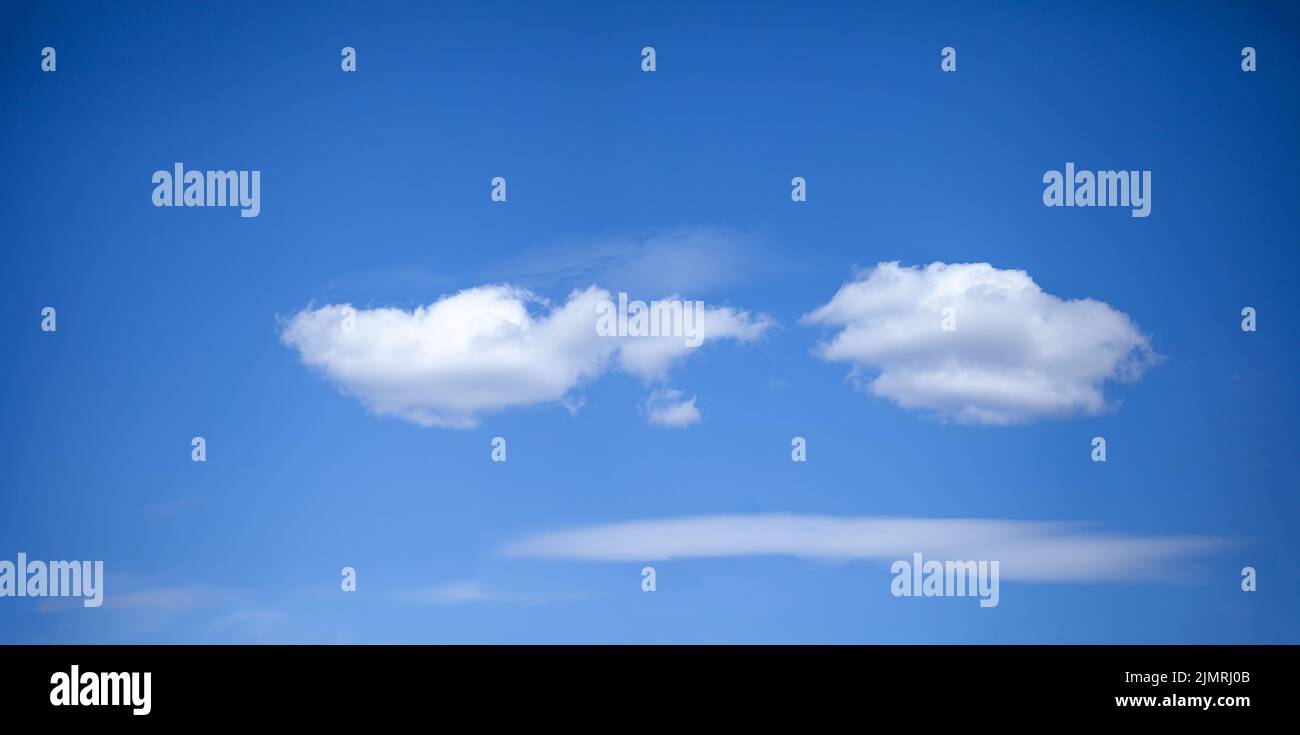 Wolken am blauen Himmel. Sieht aus wie Emoji. Stockfoto