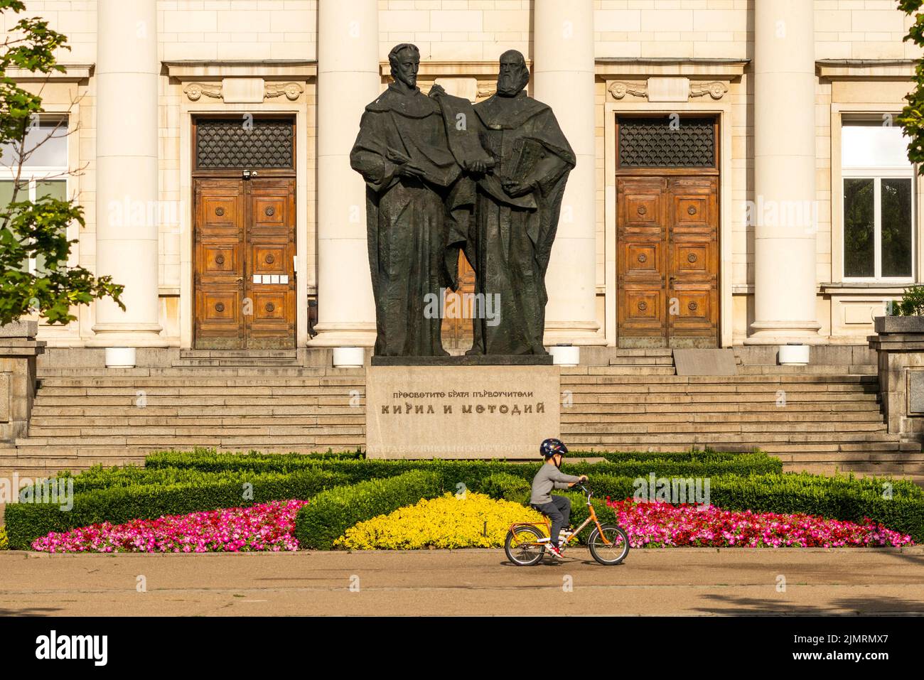 Kleiner Junge, der an der Statue der Brüder Cyrill und Methodius in der Nationalbibliothek in Sofia, Bulgarien, Osteuropa, Balkan, EU, mit dem Fahrrad unterwegs ist Stockfoto