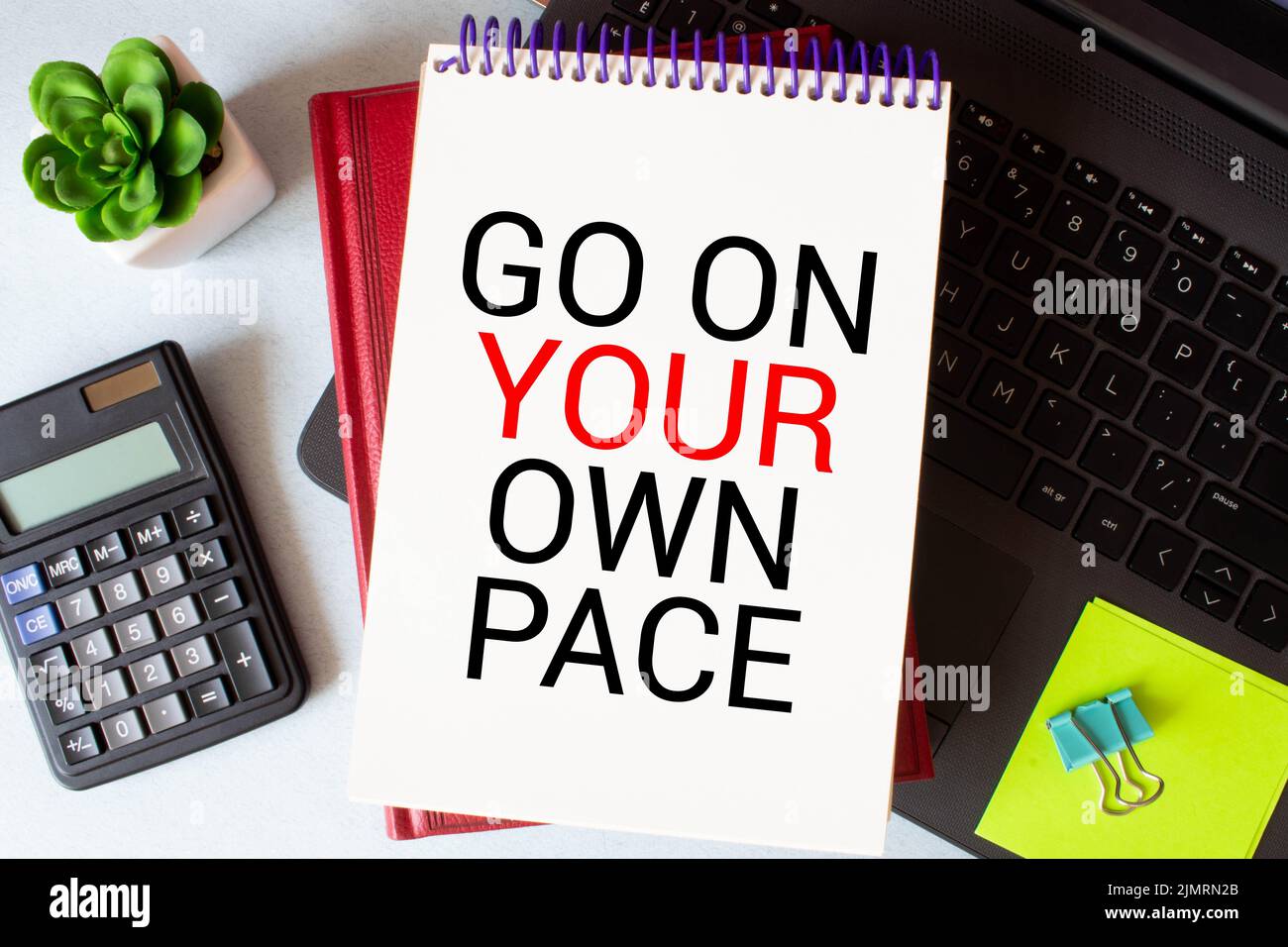 Retro-Effekt und getöntes Bild einer Frau, die eine Notiz mit einem Füllfederhalter auf ein Notizbuch schreibt. Handgeschriebener Text Gehen Sie in Ihrem eigenen Tempo als Erfolg und evo Stockfoto