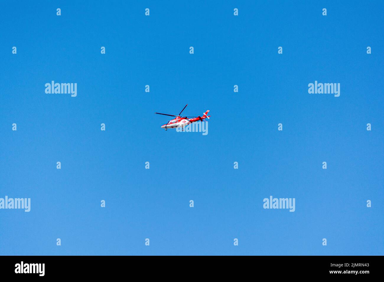 Ein medizinischer Hubschrauber mit einem roten Kreuz, das im Hintergrund des blauen Himmels fliegt Stockfoto