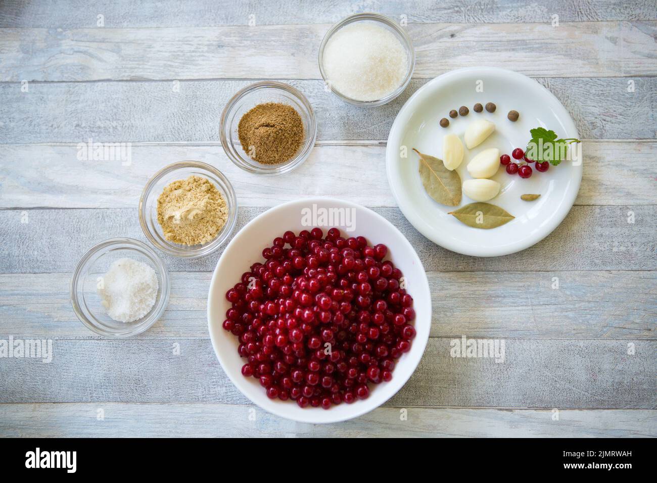 Der Prozess der Herstellung von Johannisbeersoße. Johannisbeeren und Gewürze werden in Glasschüsseln zubereitet. Stockfoto