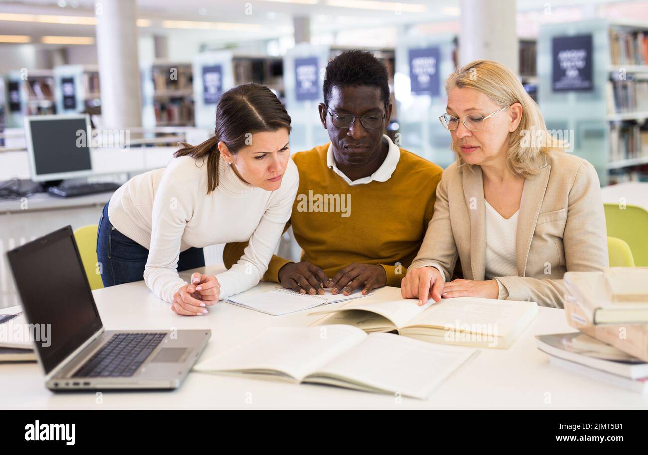 Tutorin hilft Studenten, die sich auf die Prüfung in der Bibliothek vorbereiten Stockfoto