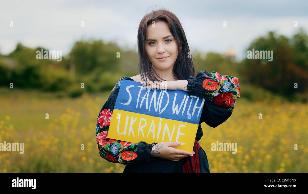 Stilvolle kaukasische Mädchen Frau Aktivistin trägt patriotische nationale ukrainische Kleid junge hübsche Dame mit demonstrierenden Pappe Zeichnung blau gelb Stockfoto