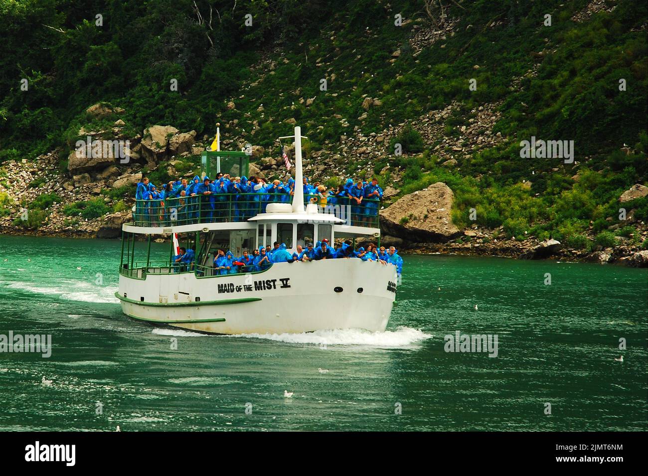 Auf einem Fährschiff werden Passagiere und Touristen mit blauen Slickers befördert, während die Maid of the Mist in Richtung Niagara Falls fährt Stockfoto