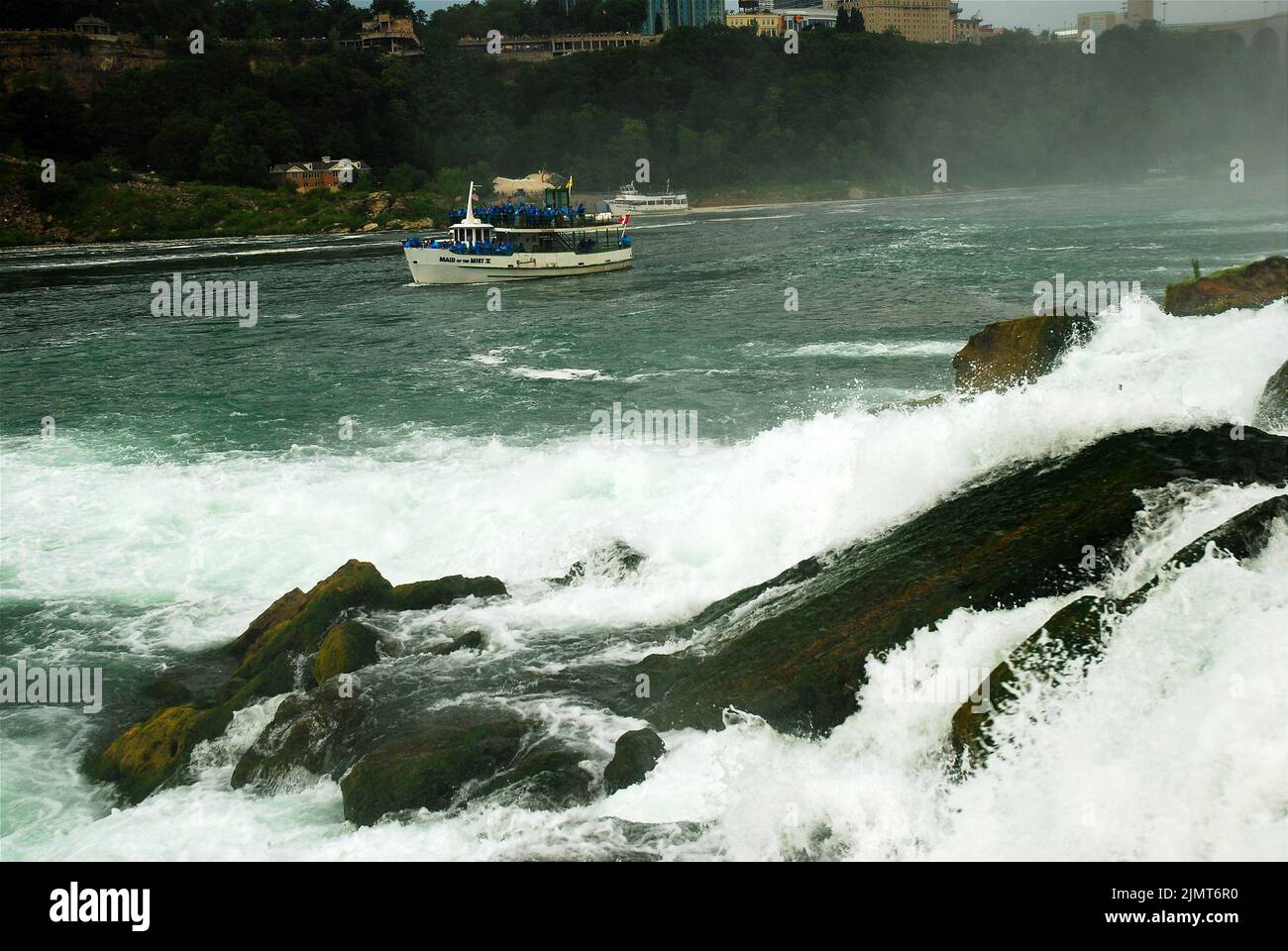 Passagiere auf dem „Maid of the Mist“-Tourboot fahren mit blauen Poncho-Regenmänteln an den American Falls in Niagara Falls vorbei Stockfoto