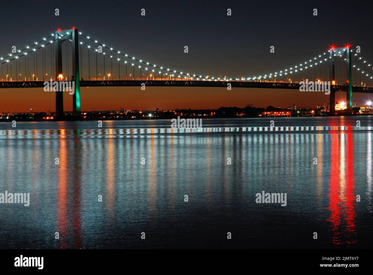 Die Lichter der Throgs Neck Bridge, die die Bronx und Queens in New York City verbindet, spiegeln sich im ruhigen und stillen Wasser wider Stockfoto