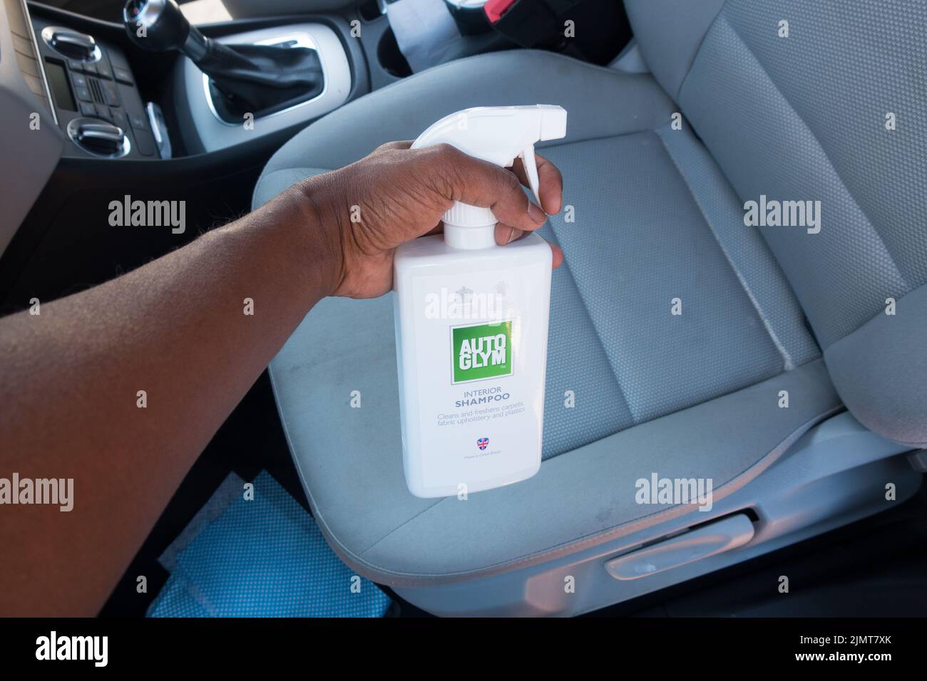Erwachsene Mann sprühen Auto Innenraum Shampoo Reinigungsflüssigkeit auf Stoff Sitz Stockfoto