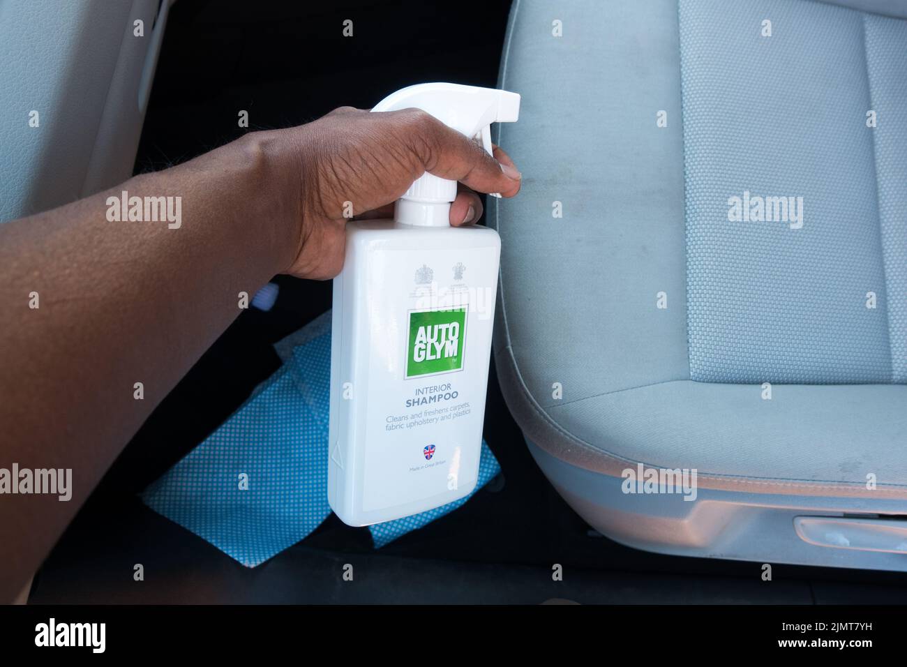 Erwachsene Mann sprühen Auto Innenraum Shampoo Reinigungsflüssigkeit auf Stoff Sitz Stockfoto