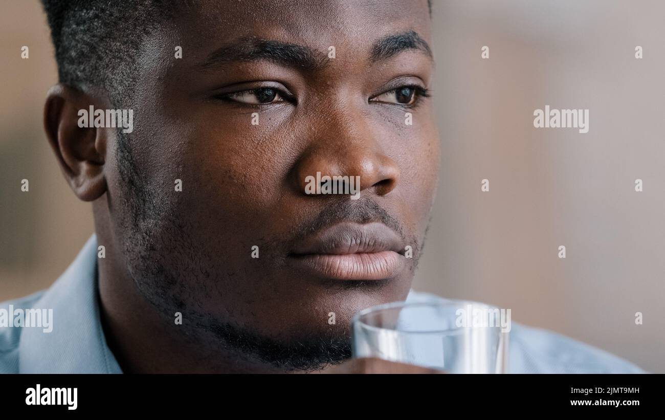 Close up Headshot african millennial man trinken reines frisches kaltes Wasser Glas gesunde Flüssigkeit leiden unter heiß machen tägliche Gewohnheit Hydrate Durst american tho Stockfoto