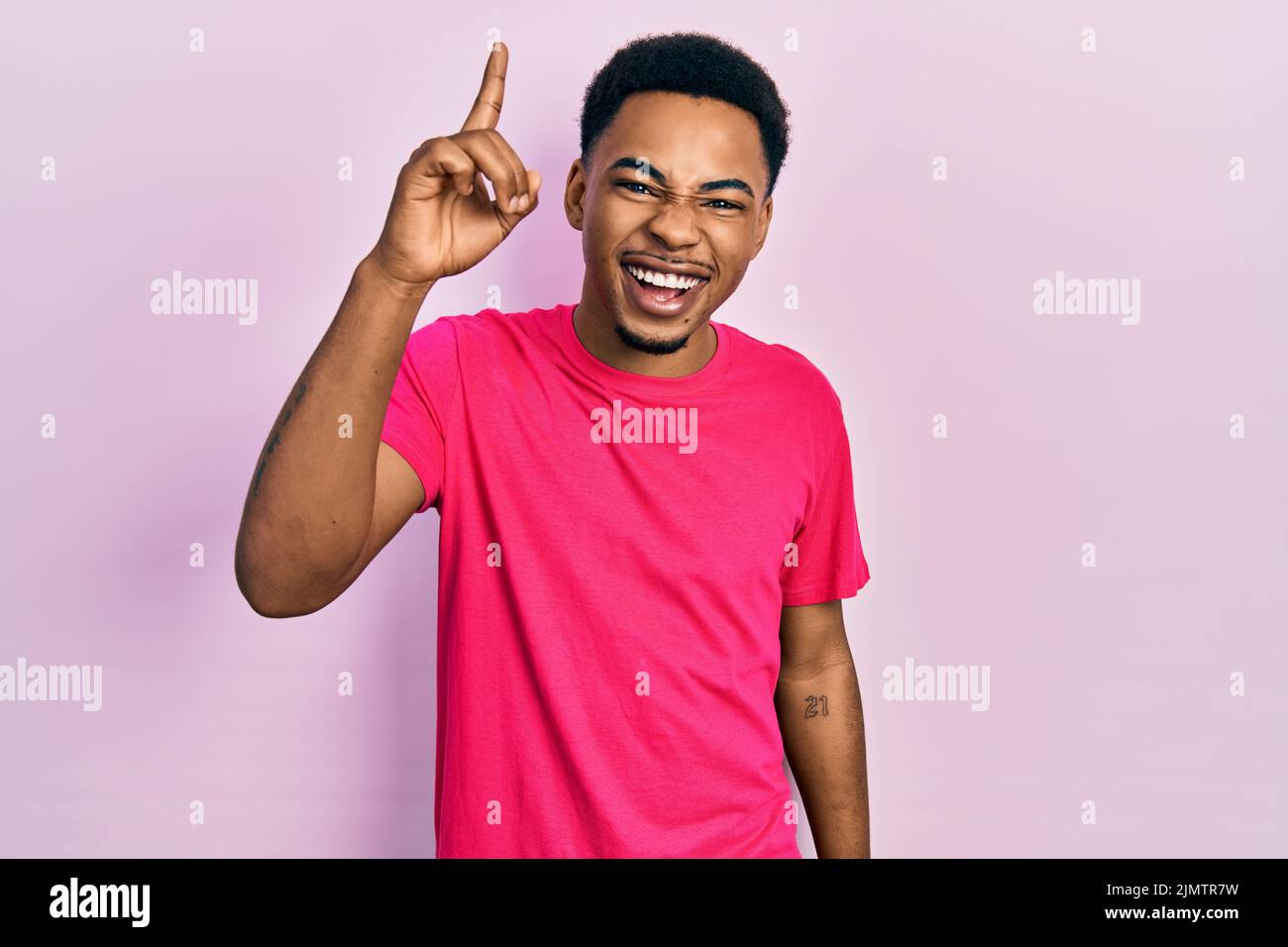 Junger afroamerikanischer Mann mit Casua T-Shirt zeigt Finger nach oben mit erfolgreicher Idee. Verlassen und glücklich. Nummer eins. Stockfoto
