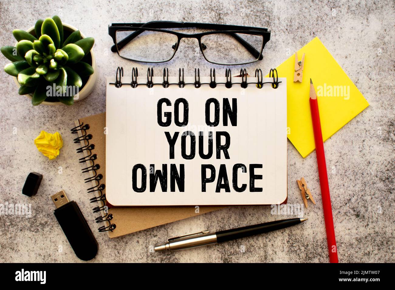 Retro-Effekt und getöntes Bild einer Frau, die eine Notiz mit einem Füllfederhalter auf ein Notizbuch schreibt. Handgeschriebener Text Gehen Sie in Ihrem eigenen Tempo als Erfolg und evo Stockfoto