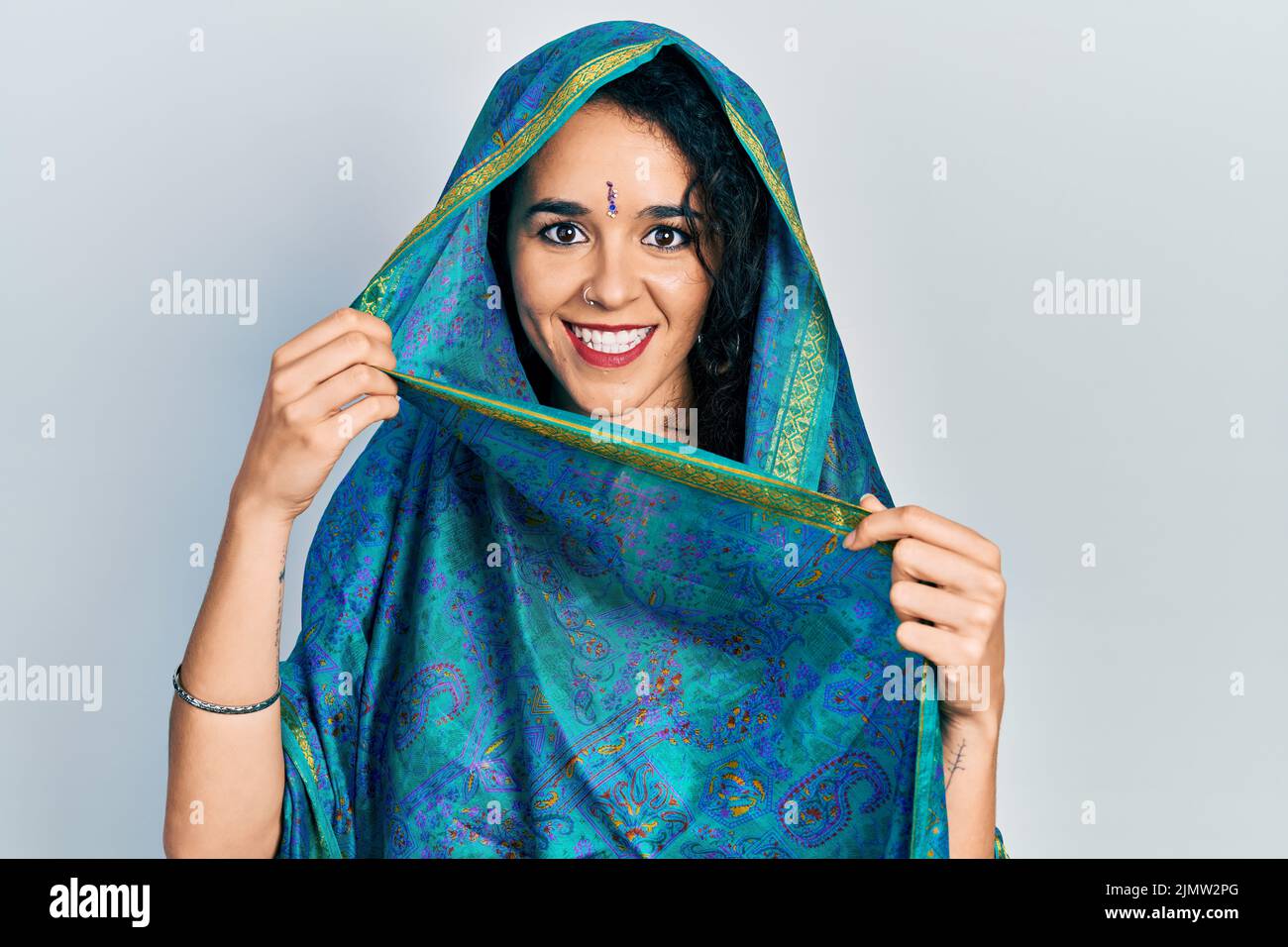 Junge Frau in Bindi, die traditionelle indische Saree trägt, zeigt den Daumen nach oben zur Seite und lächelt glücklich mit offenem Mund Stockfoto