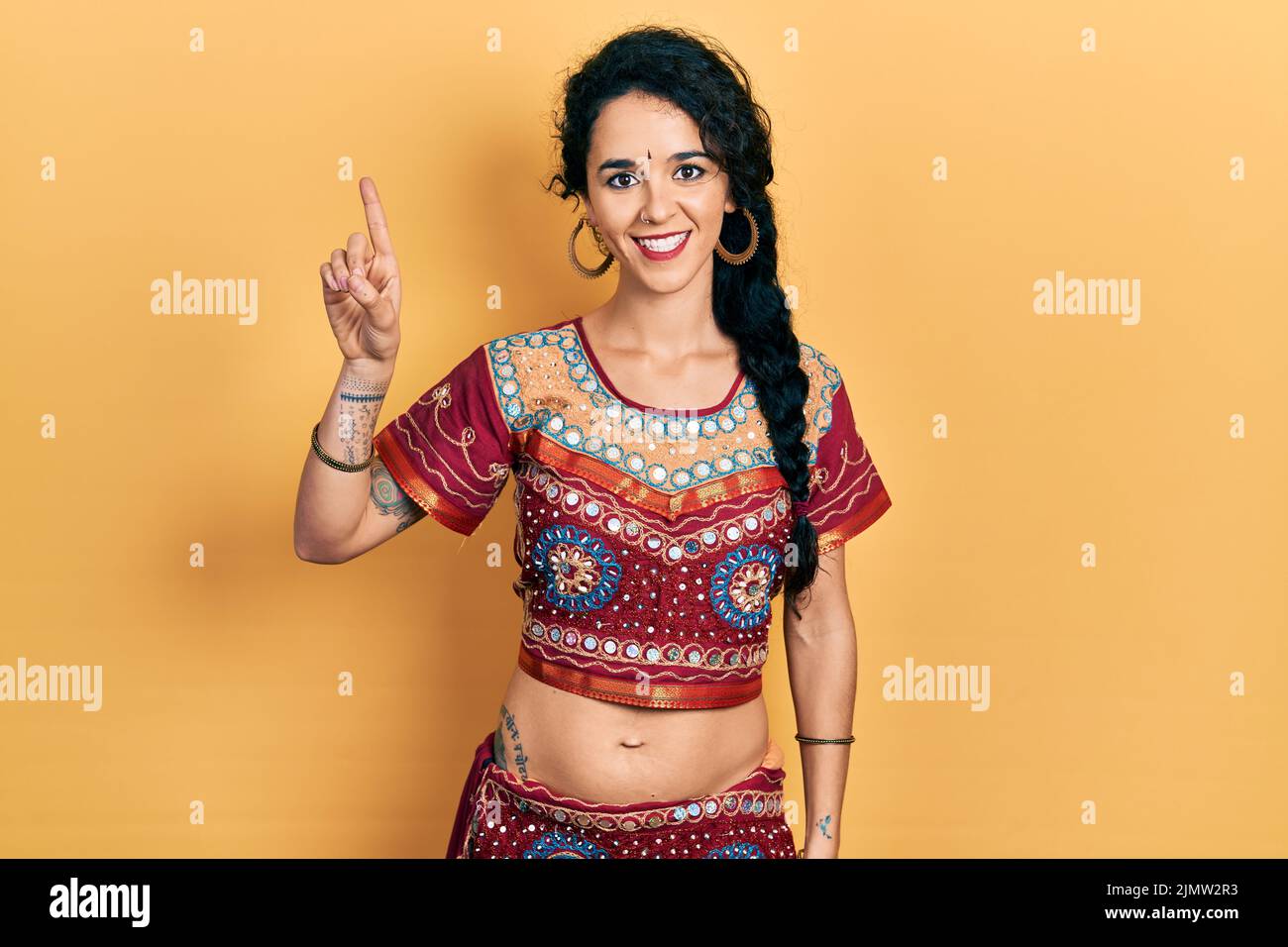 Junge Frau in Bindi- und bollywood-Kleidung, die mit dem Finger Nummer eins zeigt und zeigt, während sie selbstbewusst und glücklich lächelt. Stockfoto