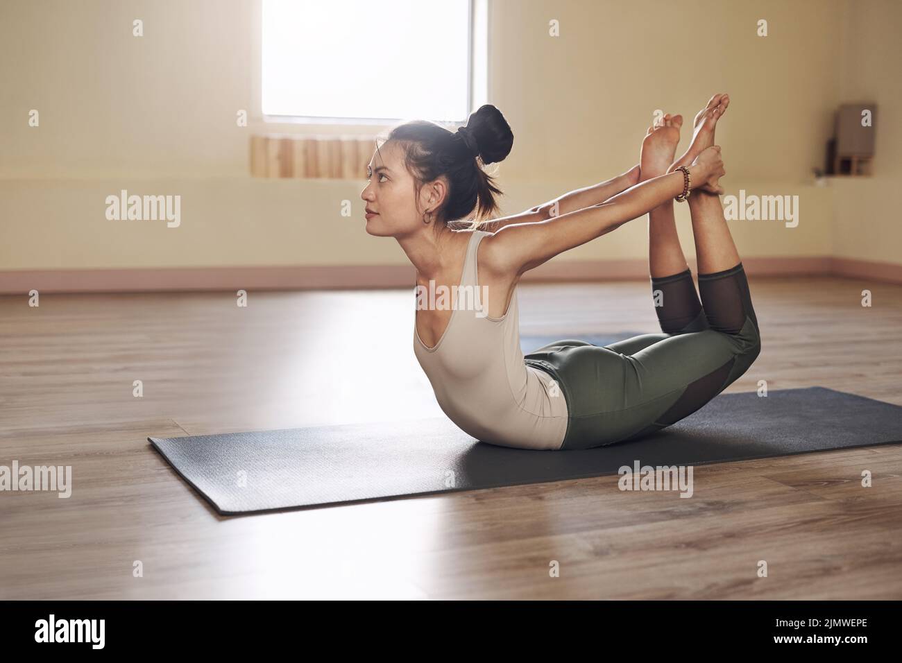 Strecke dich aus deiner Komfortzone. Ganzkörperaufnahme einer attraktiven jungen Frau, die sich in einem Yoga-Studio ausdehnt und ausübt. Stockfoto