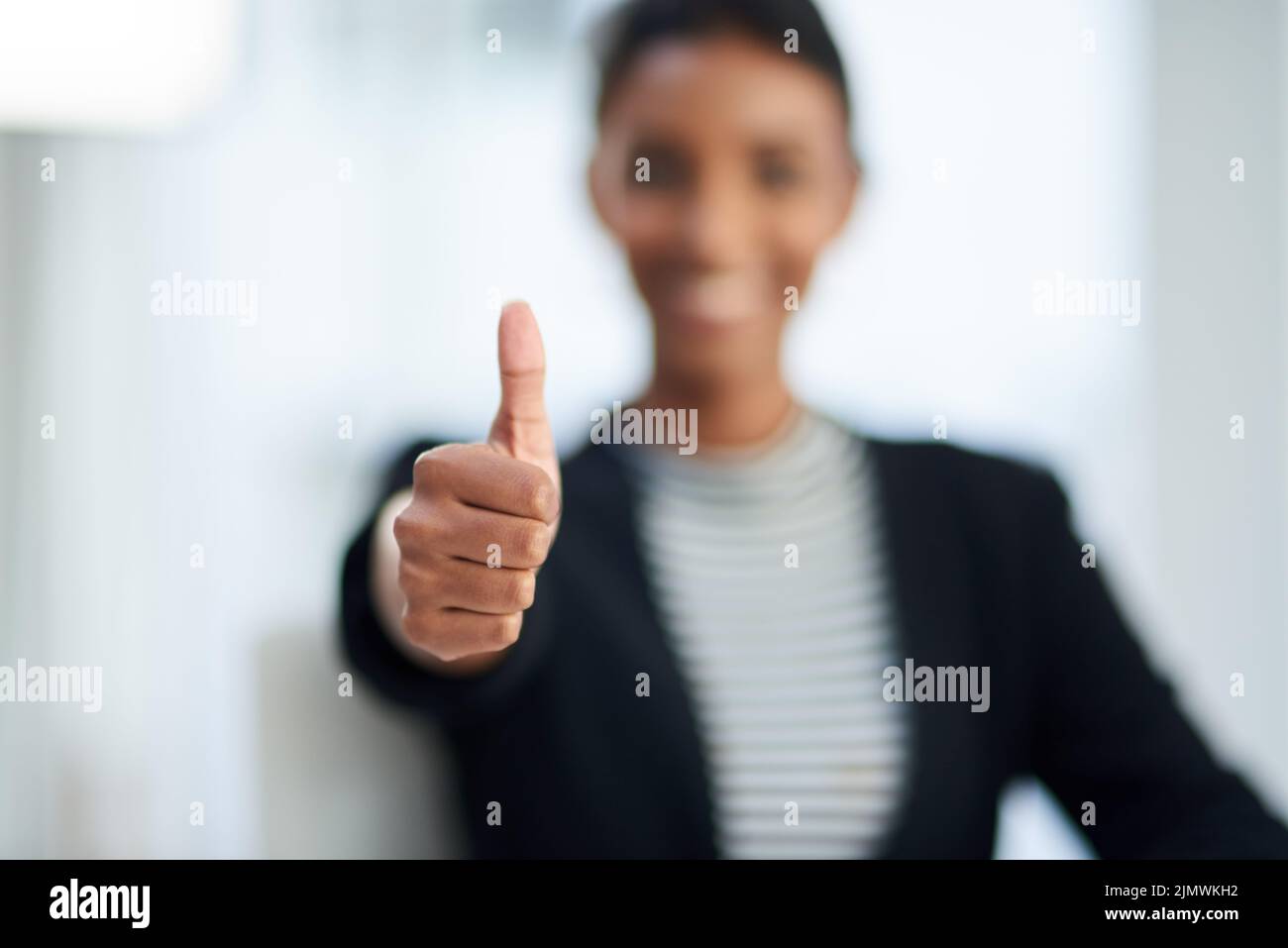 Waren alle gut zu gehen. Unfokusste Aufnahme einer jungen Geschäftsfrau, die bei der Arbeit mit den Daumen nach oben posiert. Stockfoto