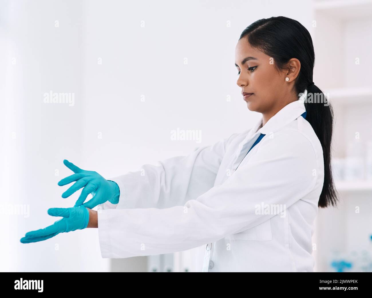 Ich denke, ich bin jetzt damit fertig. Eine attraktive junge Wissenschaftlerin, die ihre Handschuhe auszieht, während sie in einem Labor arbeitet. Stockfoto