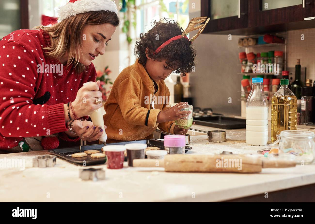 Eine fröhliche junge Frau und ihr Sohn backen zusammen in der Küche während der weihnachtszeit zu Hause Kekse. Stockfoto