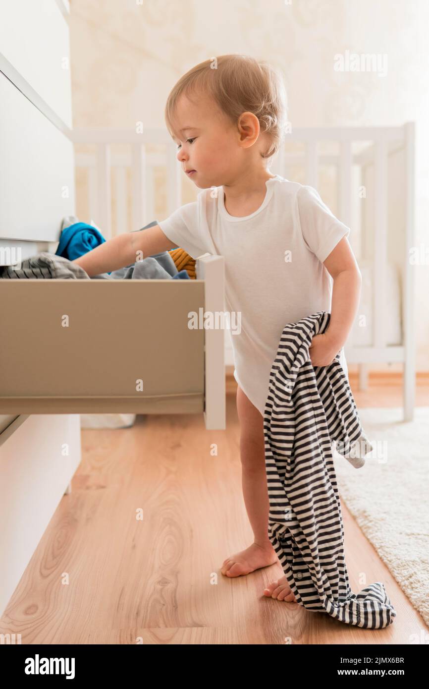 Full-Shot-Baby, das Kleidung aus der Schublade nimmt Stockfoto