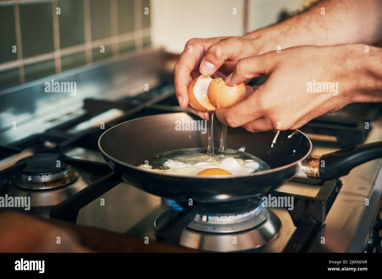 Seine Eier zum Frühstück. Ein unkenntlich Mann, der Eier in seiner Küche zu Hause braten. Stockfoto