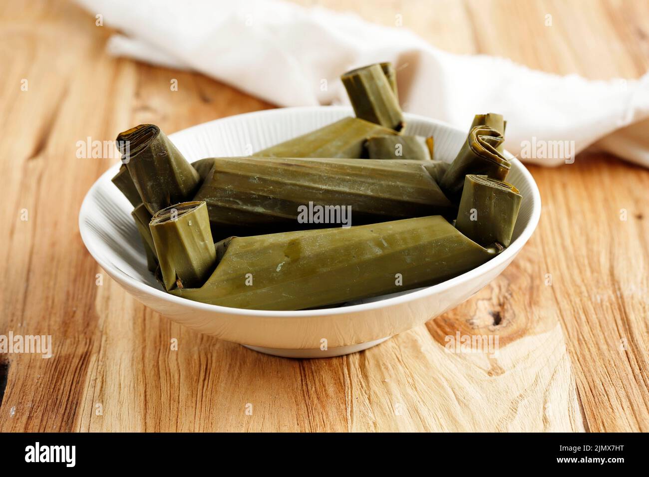 Lontong, Indonesisch gekochter Reiskuchen, Indonesisch beliebter Reiskuchen, eingewickelt mit Bananenblättern. Auf Holztisch Stockfoto