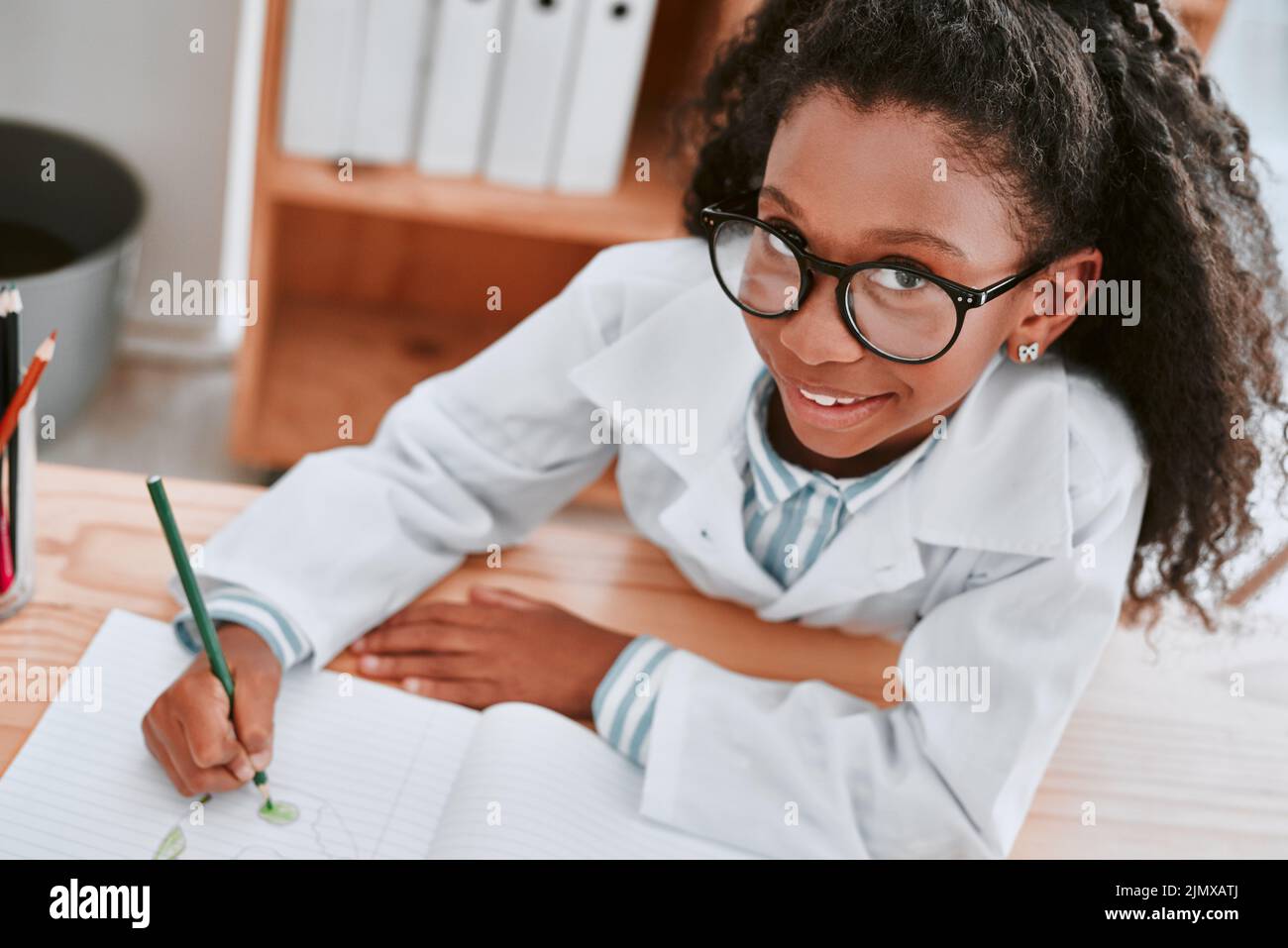 Hier komme ich. Portrait eines entzückenden jungen Schulmädchen, das ein Diagramm in ihrem Übungsbuch in der Schule in der Wissenschaft zeichnet. Stockfoto