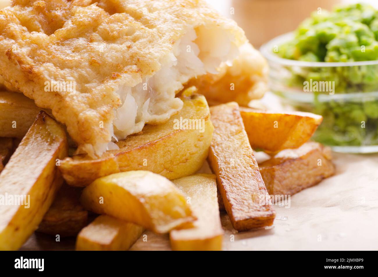 Traditionelle britische Street Food Fish und Chips mit Erbsenpüree auf Pergamentpapier Stockfoto
