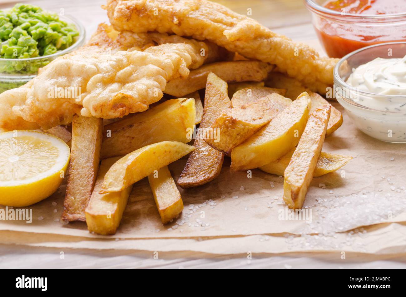 Traditionelle britische Street Food Fisch und Pommes mit Ketchup und Zahnstein Saucen und Erbsenpüree auf Papier Platte Stockfoto