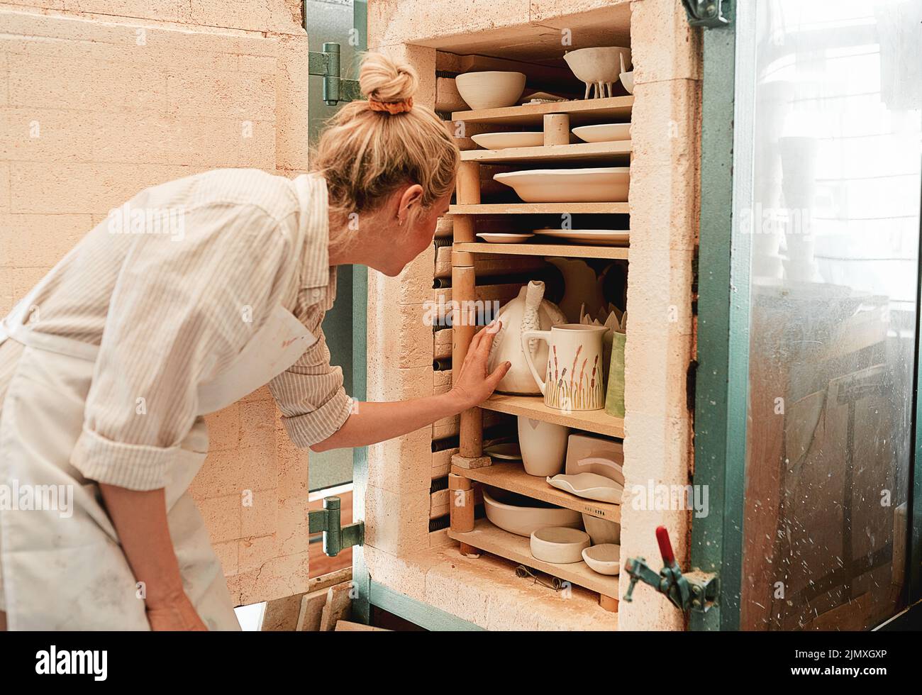Hier geht mein ganzes Design zum Trocknen. Eine Kunsthandwerkerin, die Steingut in ihren Ofen legt. Stockfoto