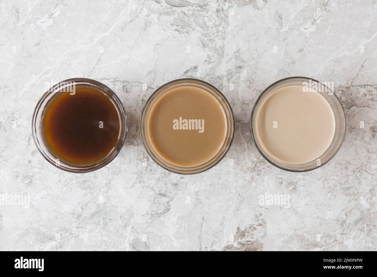 Vier Kaffeetassen Reihen sich in Marmor mit verschiedenen Mischungen Milchkaffee Stockfoto