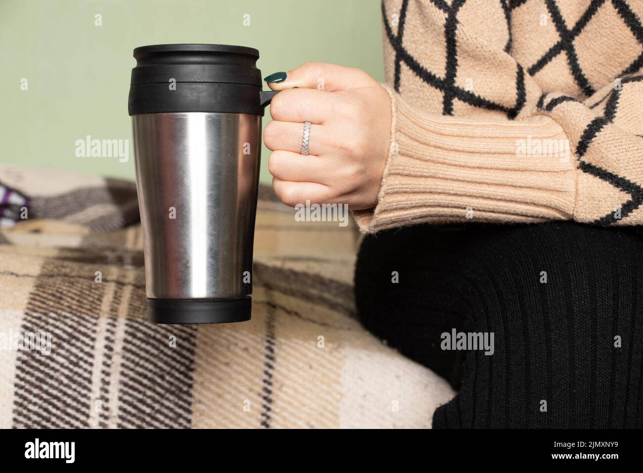Mädchen hält zu Hause einen grauen Becher in der Hand, trinkt Kaffee, einen freien Tag, eine Tasse in der Hand des Mädchens Stockfoto