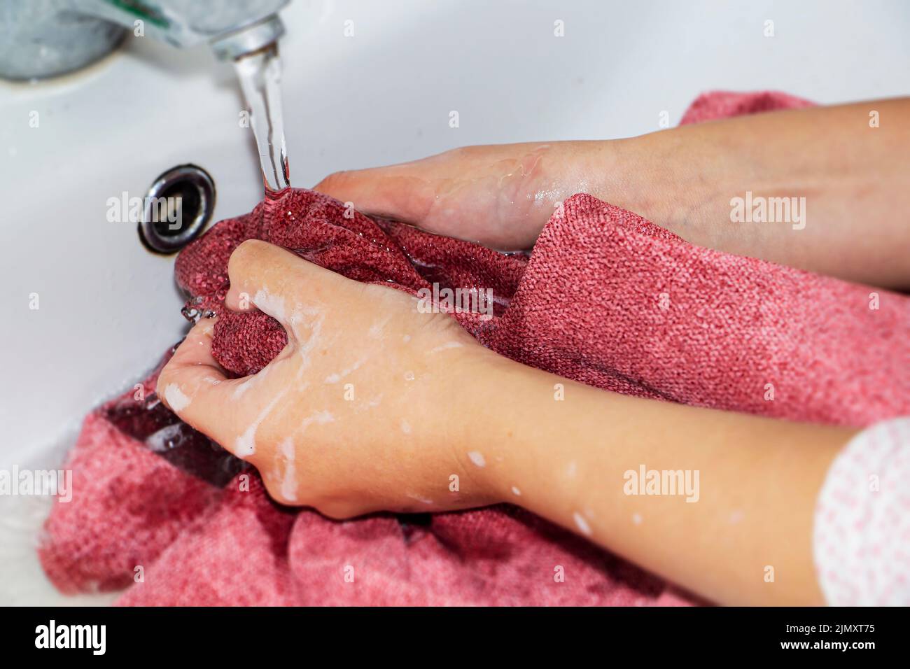 Händewaschen von farbigen Gegenständen. Damenhände waschen und auswringen farbige Dinge in Seifenwasser Stockfoto
