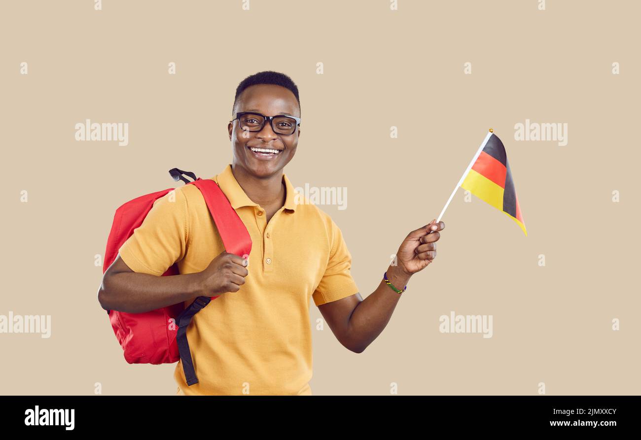Glücklicher afroamerikanischer Student mit deutschlandflagge isoliert auf hellbeigem Hintergrund. Stockfoto
