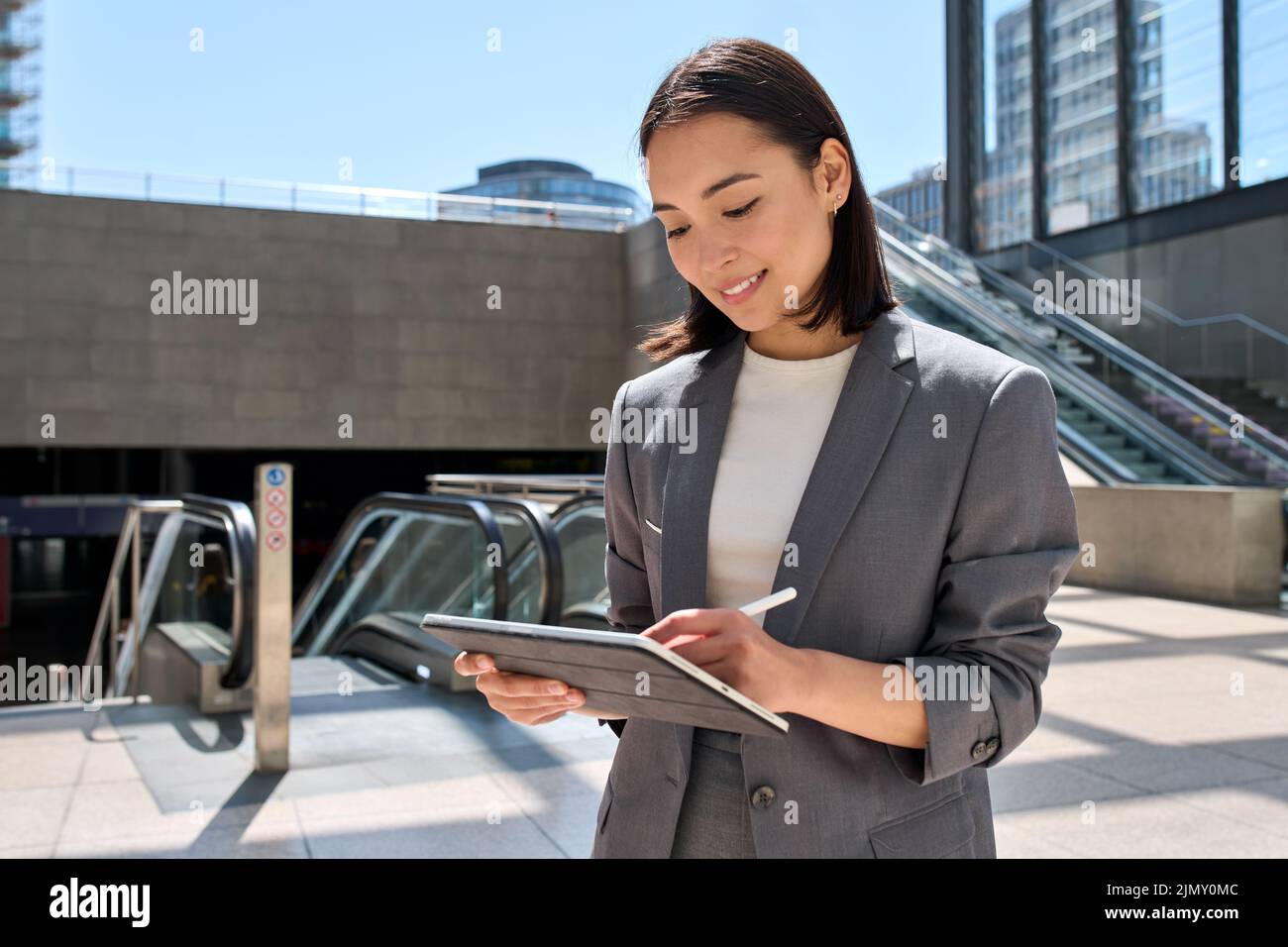 Junge asiatische Unternehmerin, die mit einem digitalen Tablet in der U-Bahn steht. Stockfoto