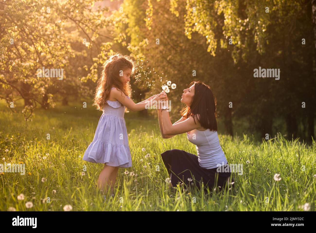 Mutter Tochter weht Dandelion Blumenpark Stockfoto