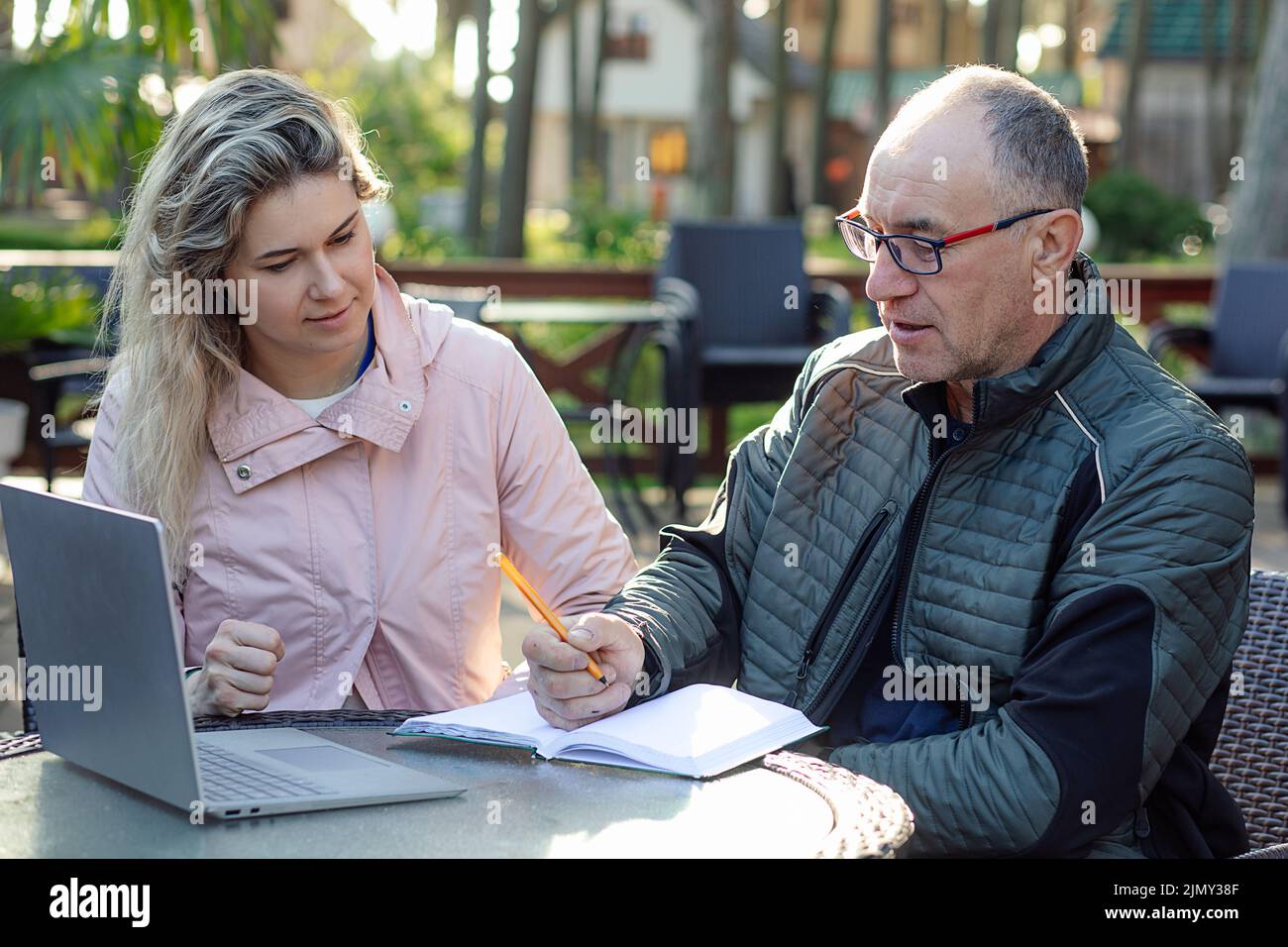 Porträt eines ernsthaften Mannes mittleren Alters, Vater, der Notizen schreibt, jungen Frauen zuhört, Informationen im Café diskutiert. Stockfoto