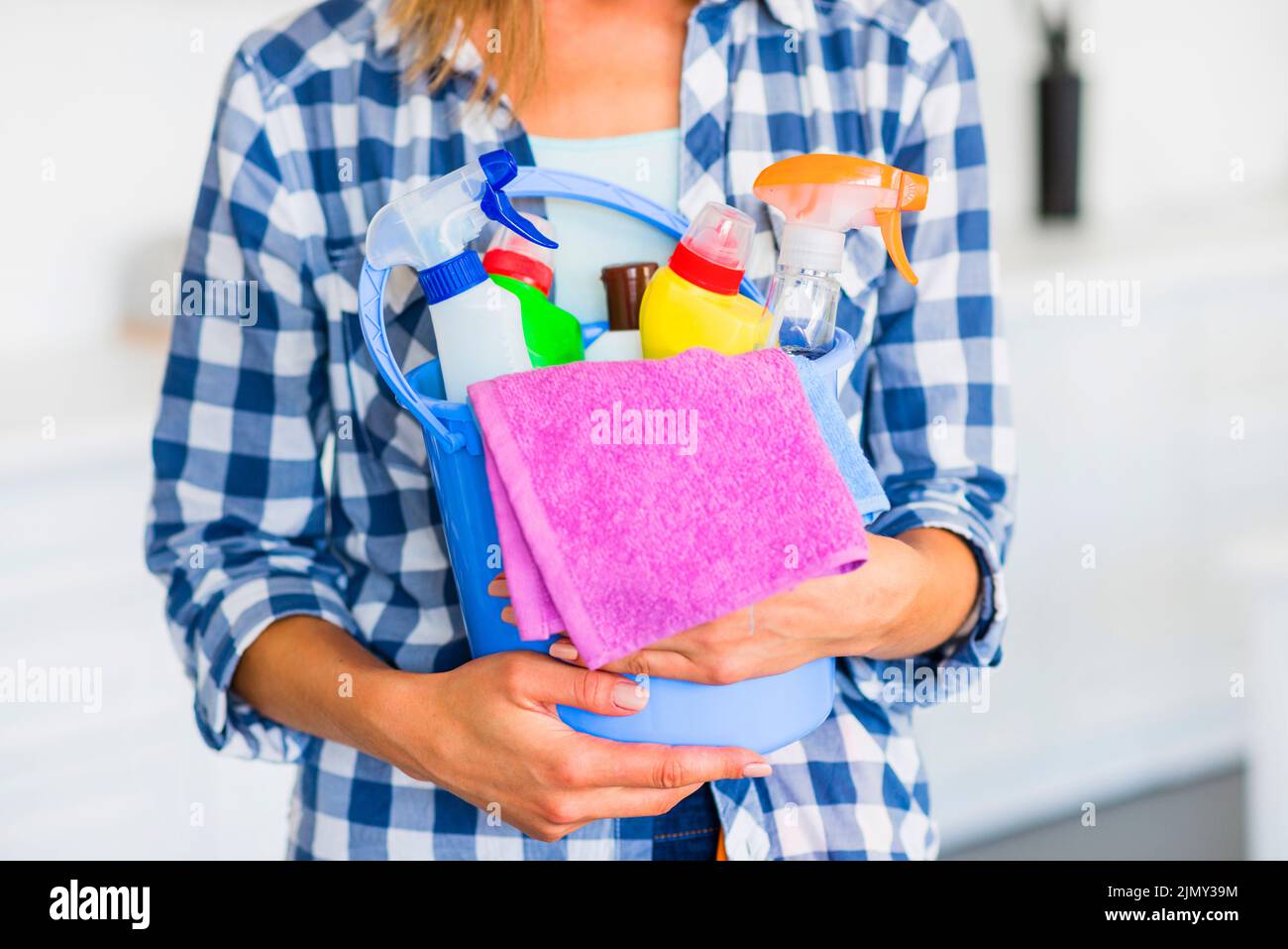 Der Hausmeister in der Mitte hält einen blauen Eimer mit Reinigungsgeräten Stockfoto