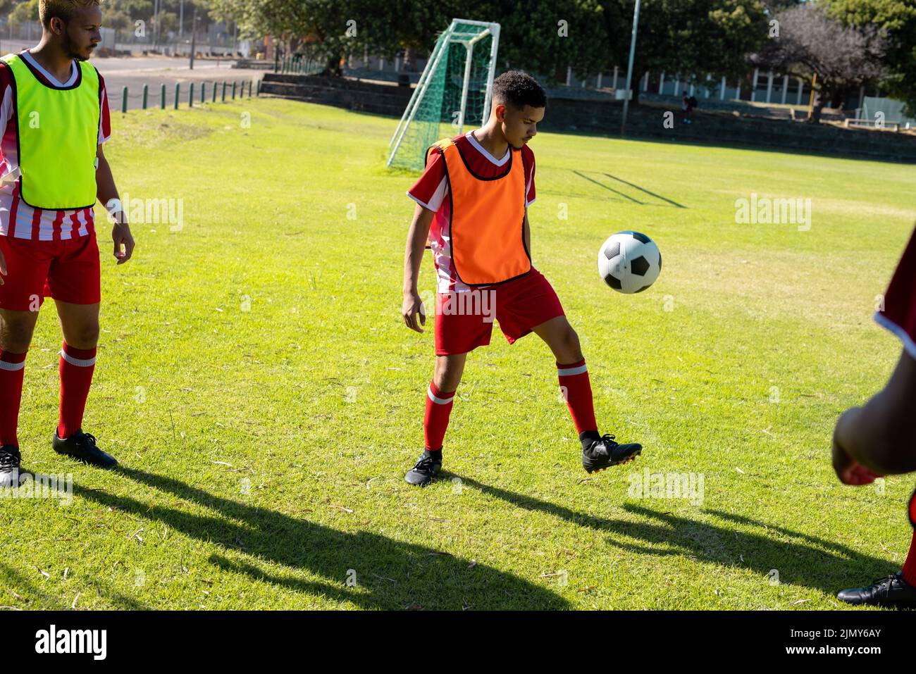 Kaukasischer männlicher Spieler, der auf dem Rasen auf dem Spielplatz einen Teamkollegen beim Freestyle-Fußball ansieht Stockfoto