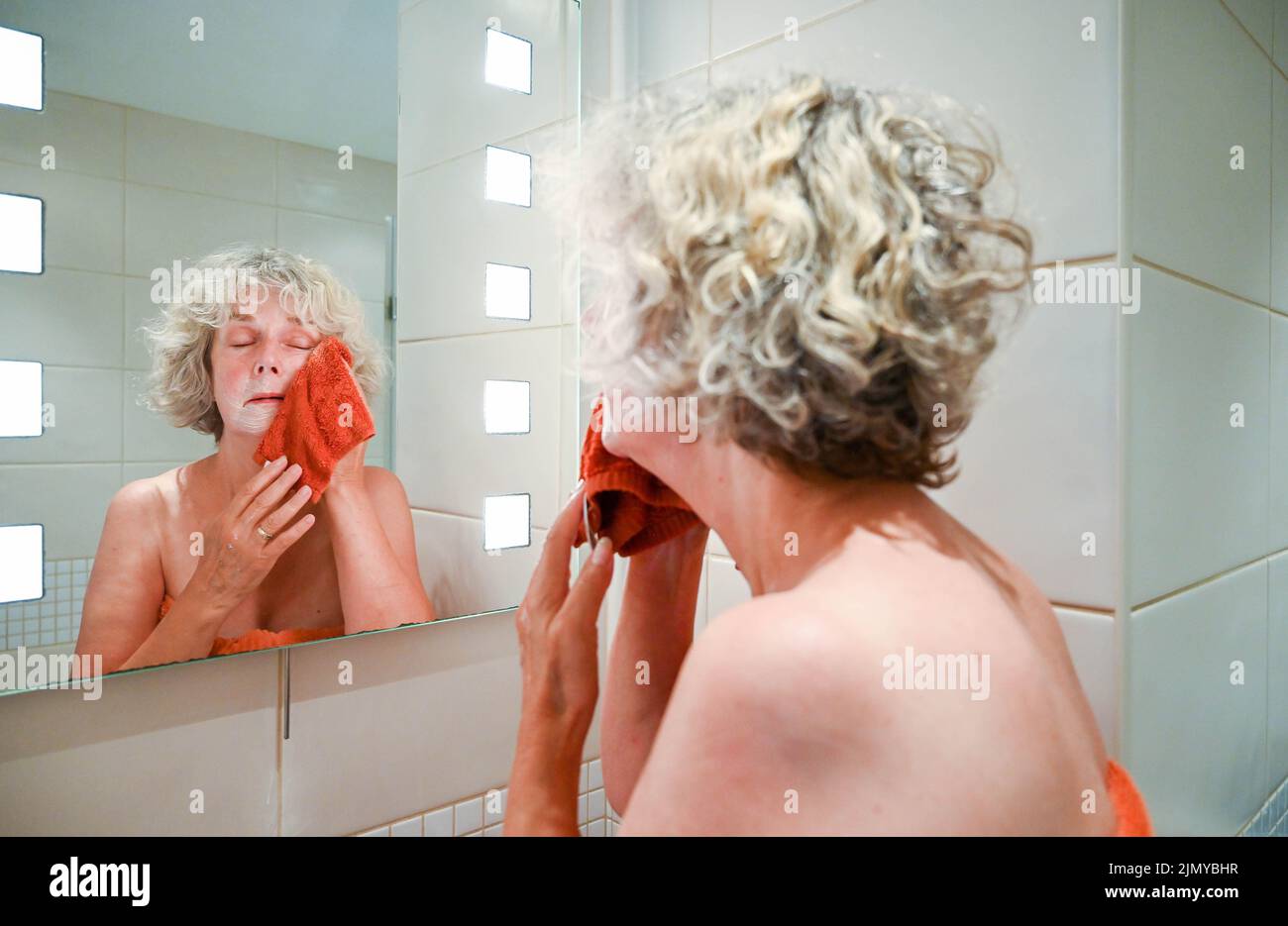 Frau, die mit einem Flanell und Seife am Waschbecken im Badezimmer wascht, um Wasser zu sparen, da in einigen Gebieten Großbritanniens Wasserknappheit herrscht Stockfoto