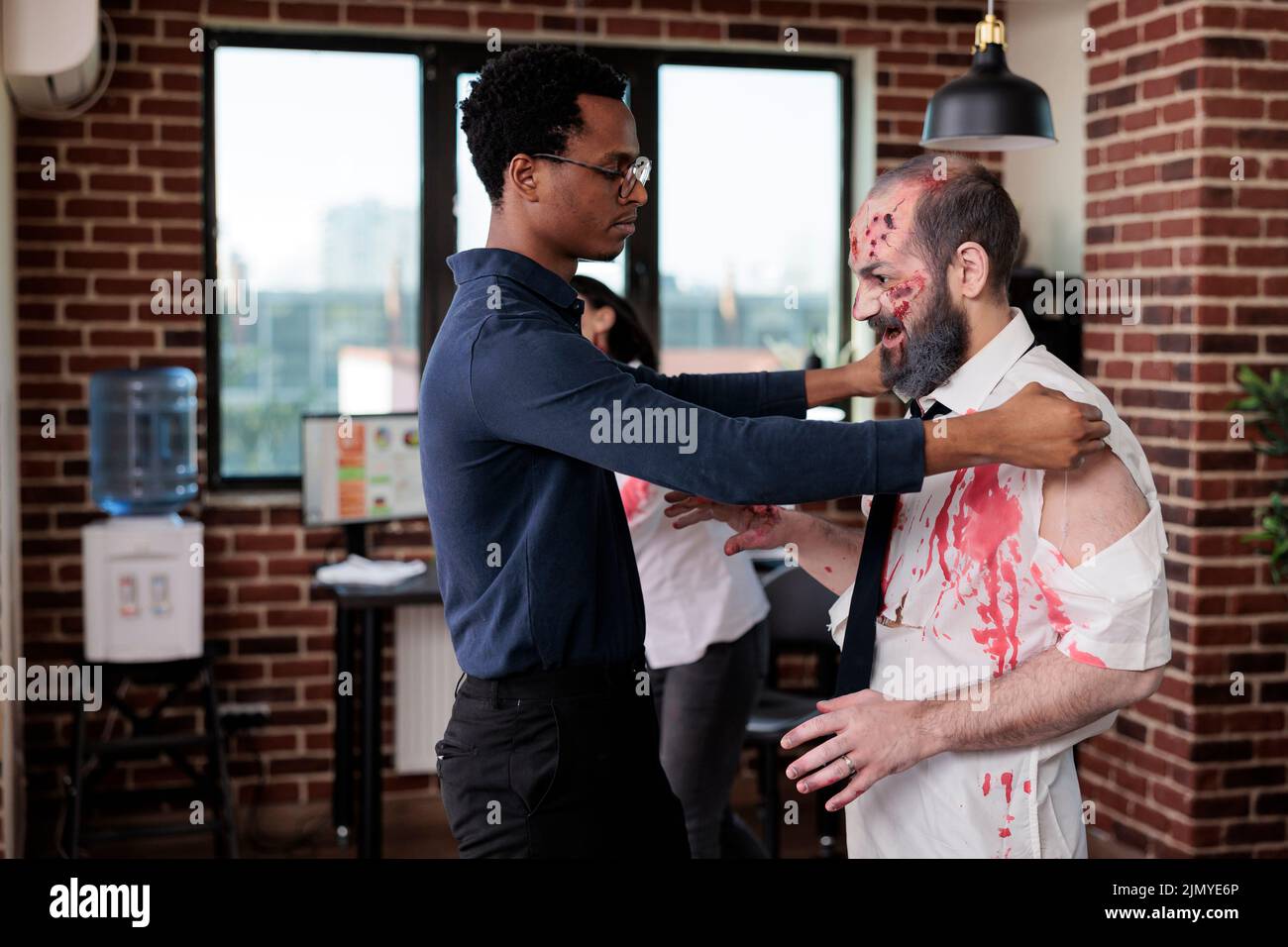 Gruseliger unheimlicher Zombie, der am Arbeitsplatz mit dem Mann spricht, makabre grausame Monster-Leiche im Geschäftsbüro, die aggressiv und gefährlich handelt. Untoter, untoter Teufel mit blutigen Wunden im Firmenraum. Stockfoto