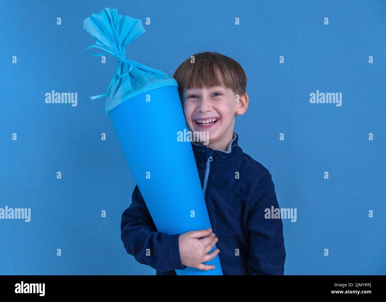 Kind hält am ersten Schultag traditionellen deutschen Süßigkeitenkegel. Junge mit einer süßen Tasche. Schulbeginn in Deutschland Stockfoto