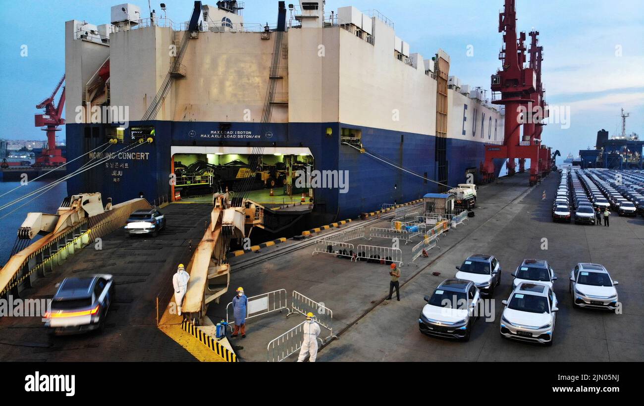 Qingdao. 7. August 2022. Das Luftfoto vom 7. August 2022 zeigt, dass Nutzfahrzeuge auf ein Ro-Ro-Frachtschiff verschifft werden, um im Hafen Qingdao in Qingdao, der ostchinesischen Provinz Shandong, nach Afrika abzureisen. Das Exportvolumen von Nutzfahrzeugen aus dem Hafen Qingdao ist in diesem Jahr im Vergleich zum Vorjahr um über 90 Prozent gestiegen. Quelle: Li Ziheng/Xinhua/Alamy Live News Stockfoto