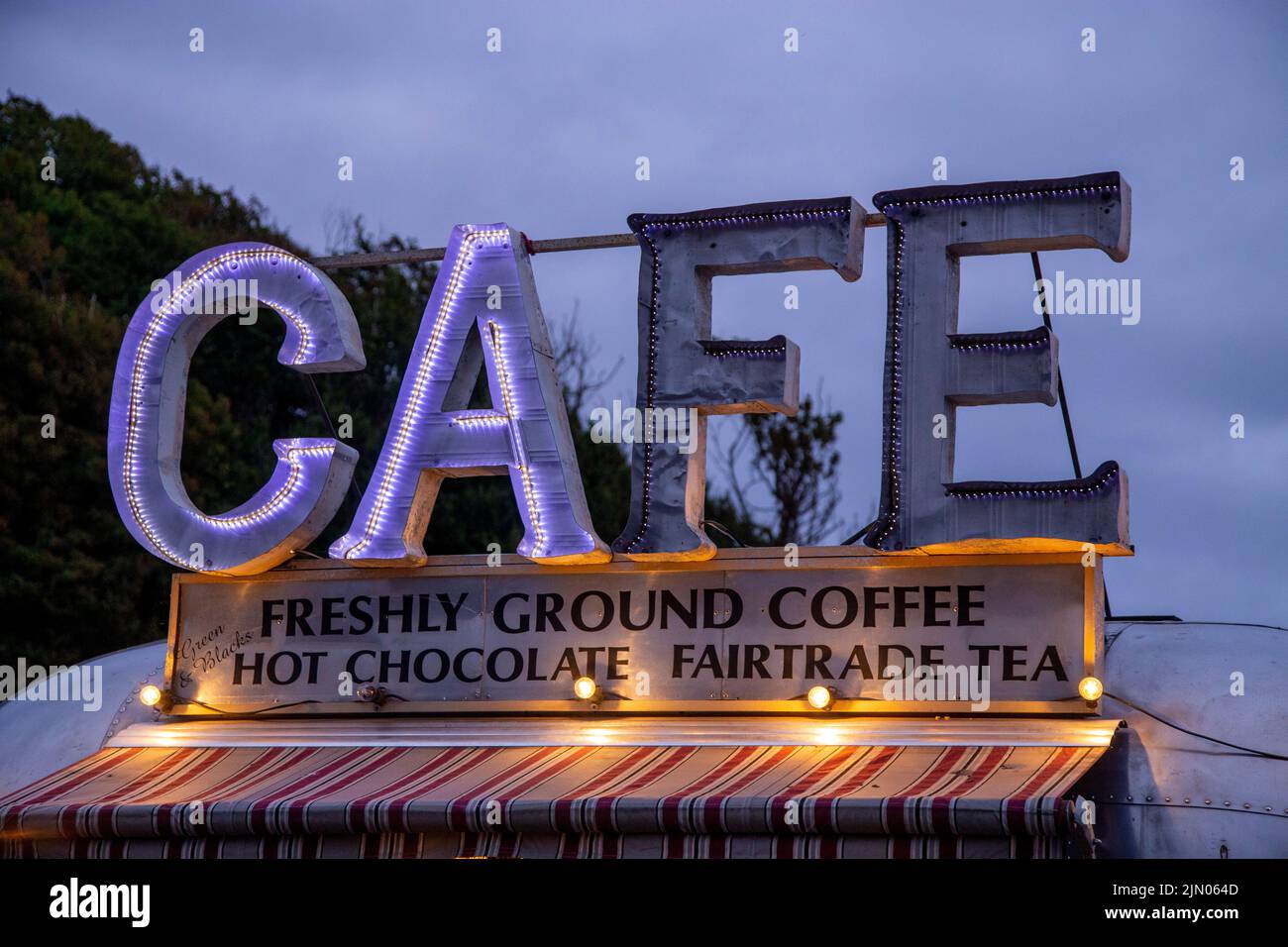 Pop-up-Café-Wohnwagen mit gebrochenem beleuchteten Schild. Essen und Kaffee im Freien, Feststand. Café-Schild.Kaffee Stockfoto