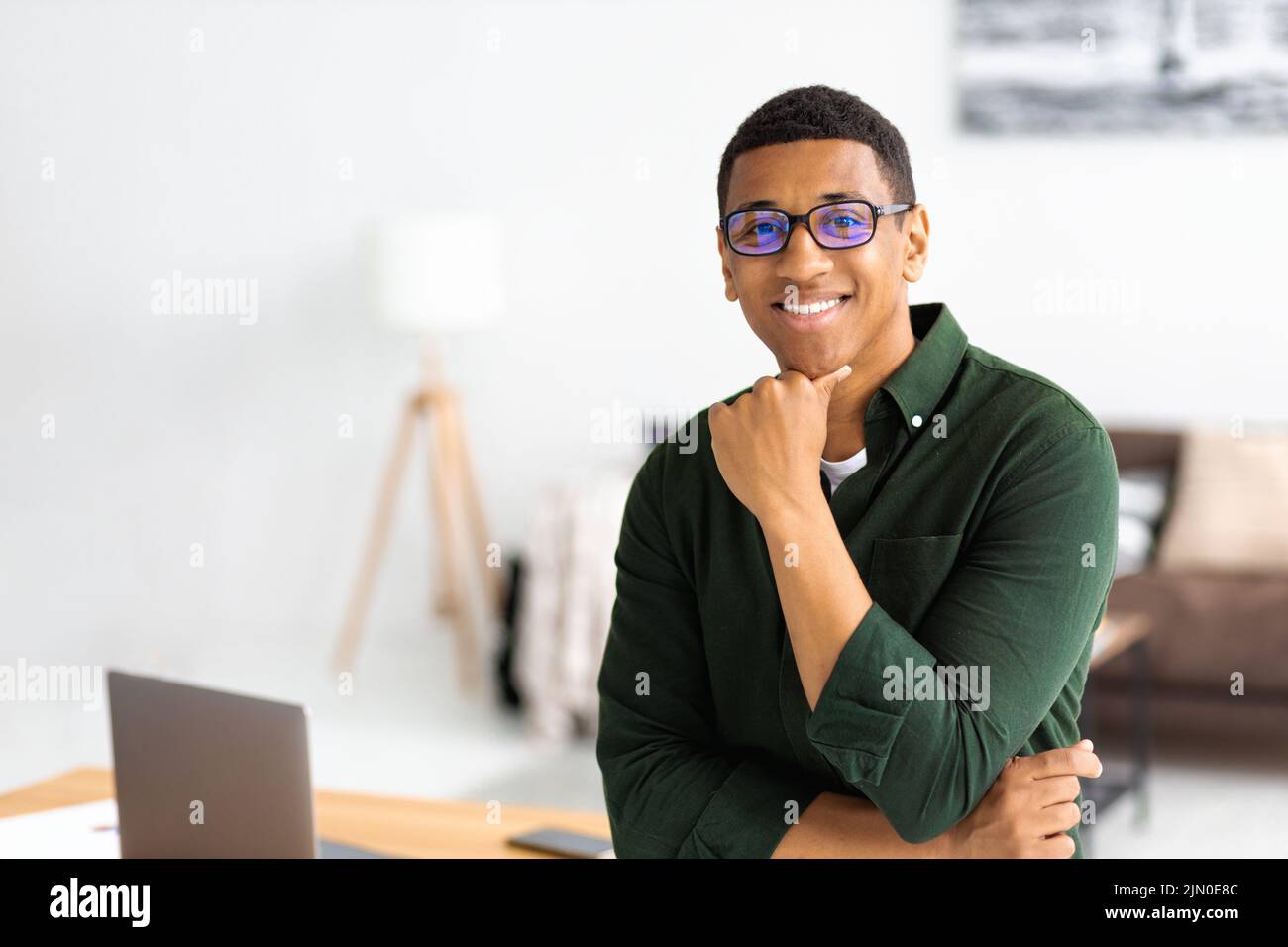 Porträt eines erfolgreichen jungen afroamerikanischen Geschäftsmannes mit Brillen, die im modernen Büro stehen Stockfoto