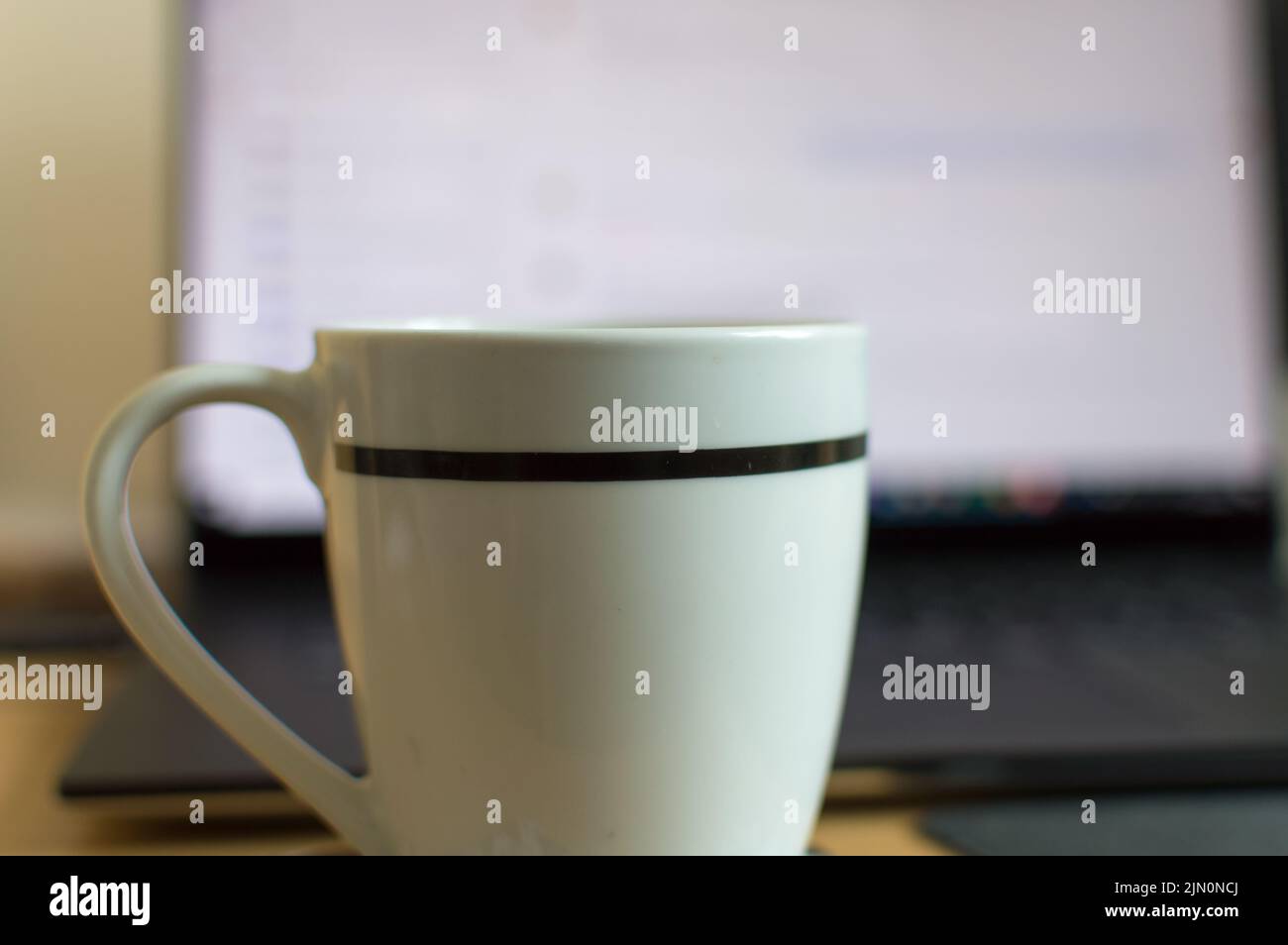 Nahaufnahme einer Tasse vor einem Laptop-Bildschirm Stockfoto