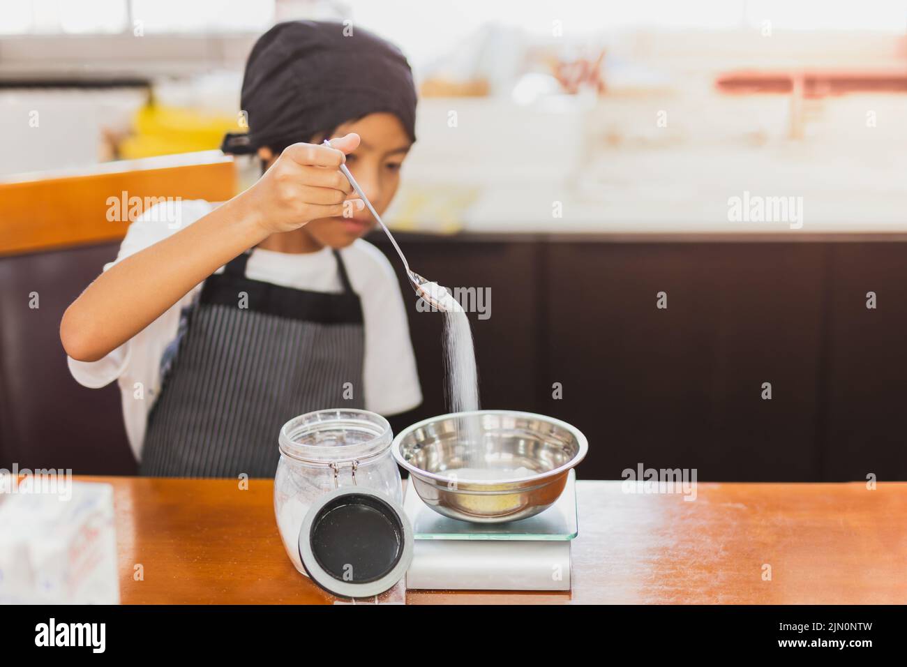 Kleiner Junge, der Zutat zum Backen in der Küche misst. Stockfoto