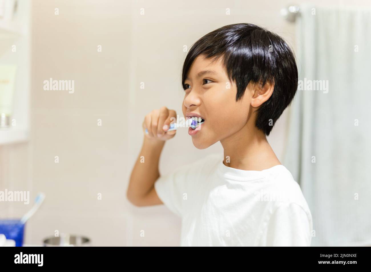 Junge, der sich im Badezimmer mit einer Zahnbürste die Zähne putzt. Stockfoto
