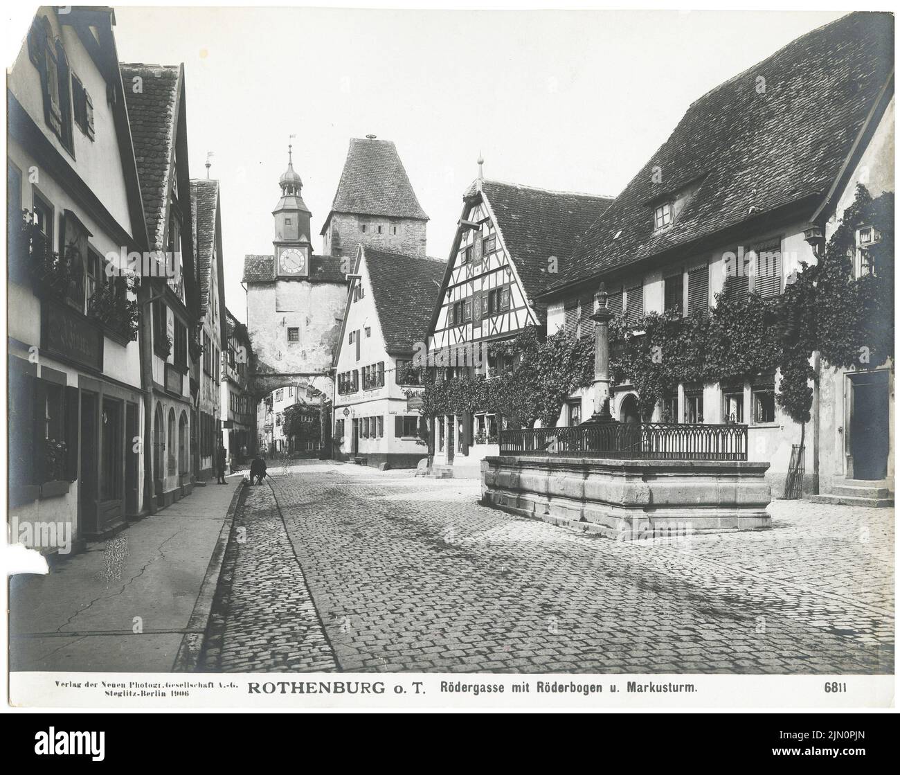 Neue Fotogesellschaft (NPG), Rödergasse mit Röderbögen und Markusturm, Rothenburg/Tauber (1906): Blick von der Rödergasse mit Röderbrunnen auf das alte Stadttor Röderbögen mit dem Markusturm aus dem 12.. Jahrhundert. Foto, 19,4 x 24,5 cm (inklusive Scankanten) Neue Photographische Gesellschaft (NPG): Rödergasse mit Röderbögen und Markusturm, Rothenburg/Tauber (1906) Stockfoto