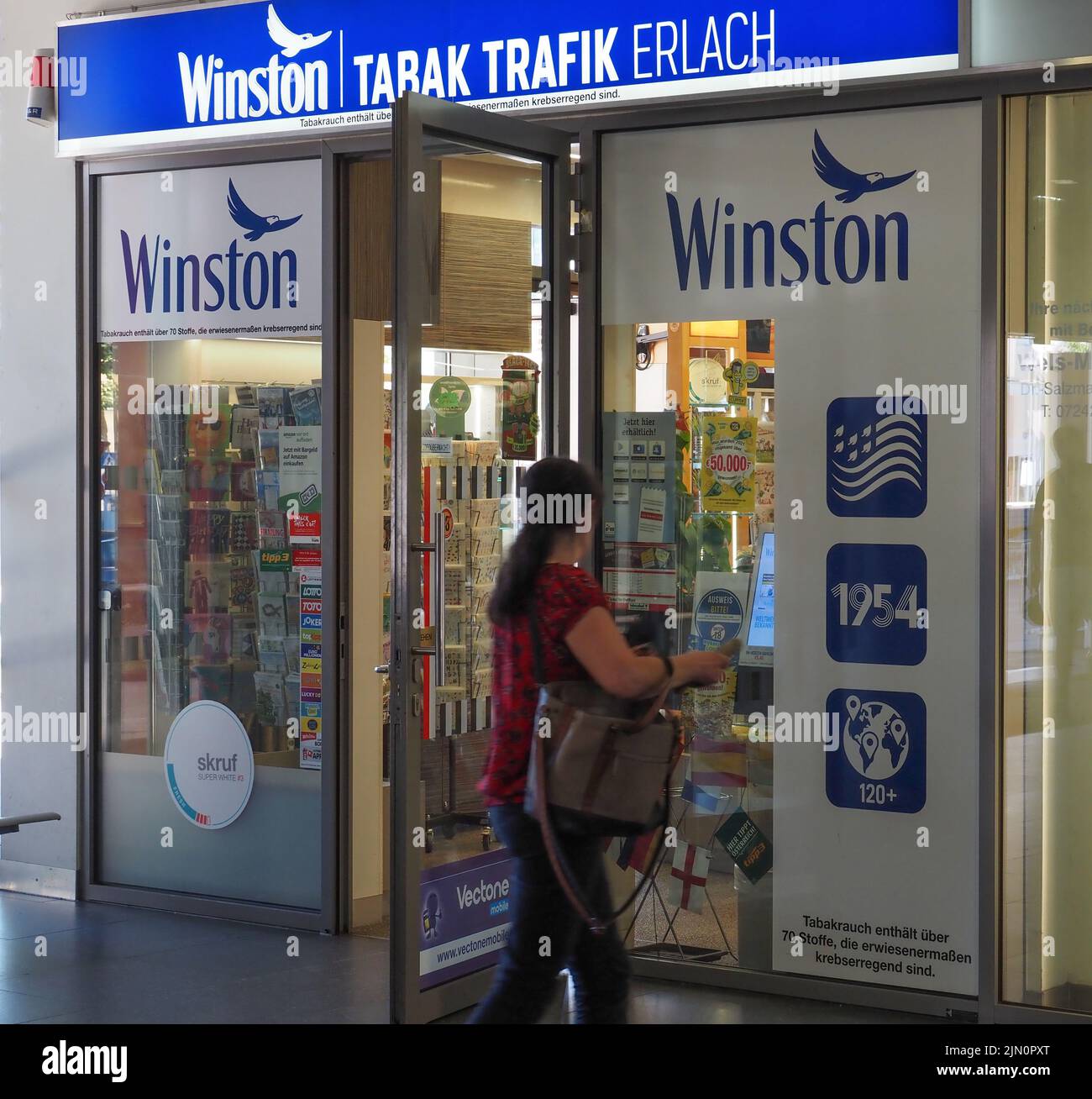 Eine Frau kommt an einem Tabakladen vorbei, der für Winston-Zigaretten wirbt. Stockfoto