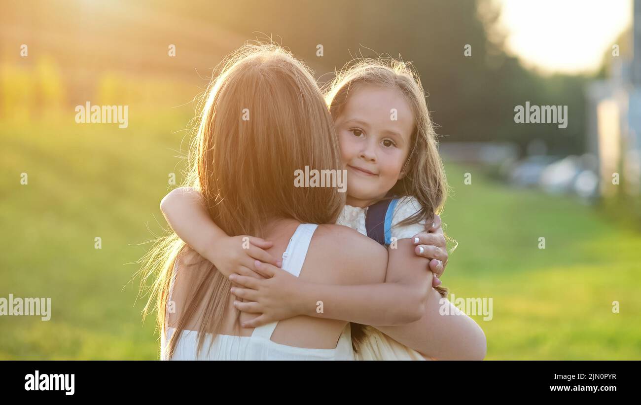 Glückliches Mädchen läuft und umarmt Mutter nach langen Schultag Stockfoto